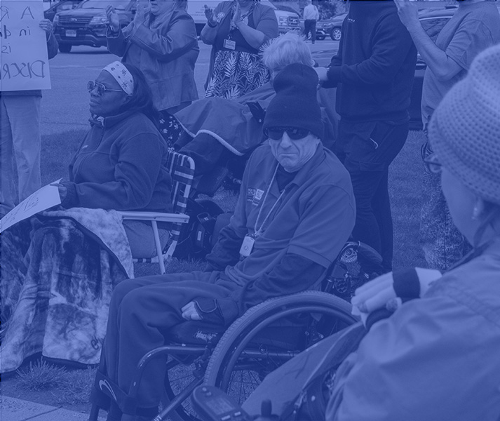 Group of people in wheelchairs in a rally crowd.