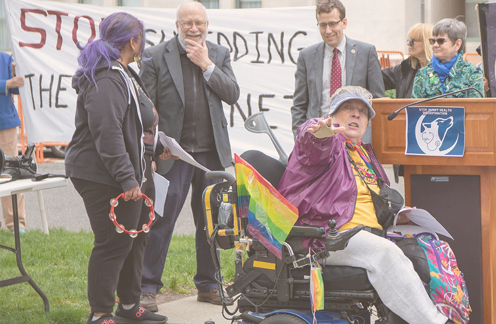 Woman in wheelchair speaking at a podium.