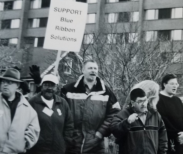 Group of KTP members marching in a rally holding a "Support Blue Ribbon Solutions" sign.